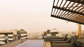 A rooftop terrace with a swimming pool, lounge chairs, and a view of the cityscape. - Exclusive, One Step Away from San Isidro (1302) (Lima)