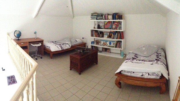 A dormitory room with two beds, a desk, a bookshelf, and a globe.