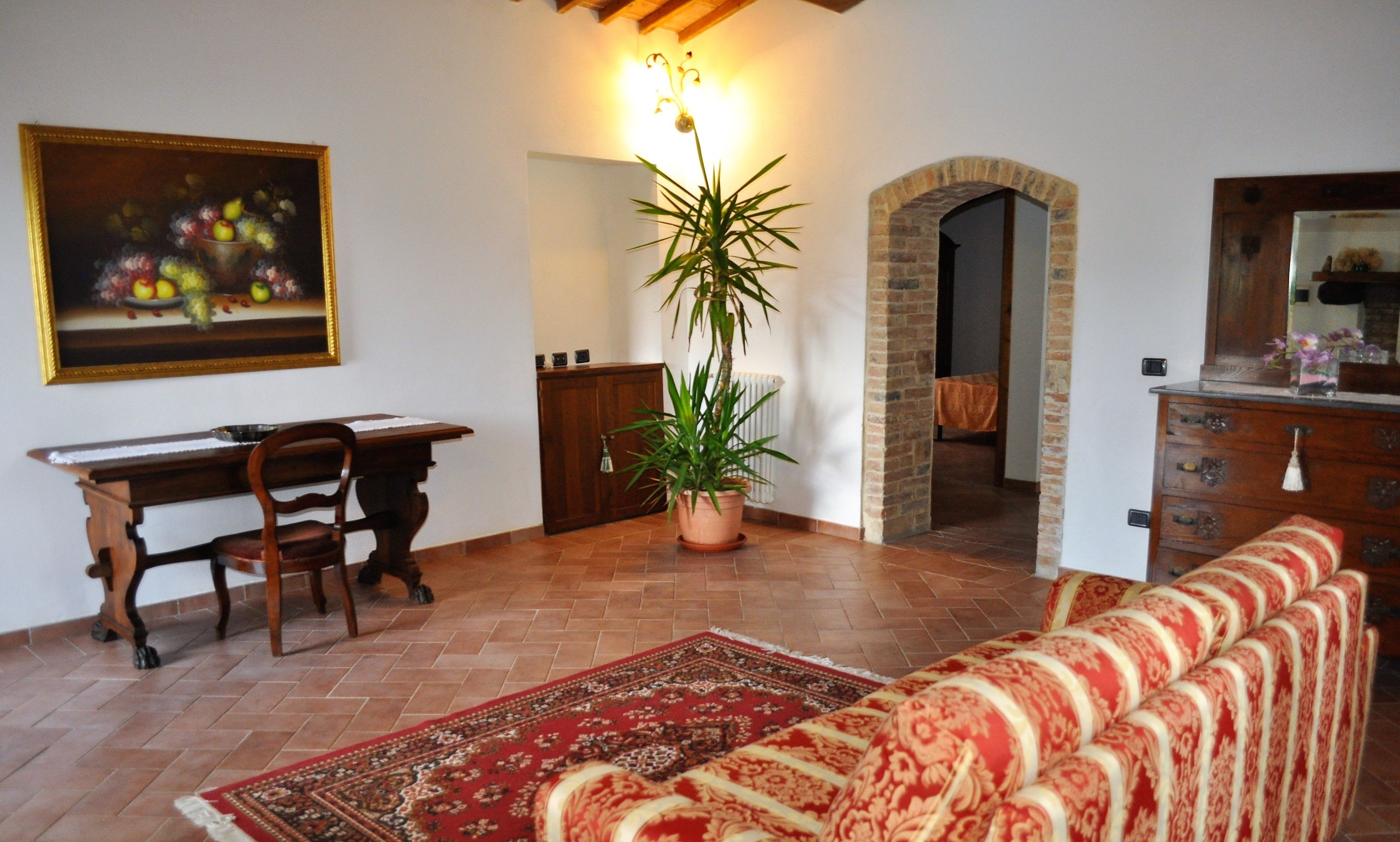 Una sala de estar con un sofá, una mesa de comedor con sillas, una planta en maceta y un cuadro en la pared.