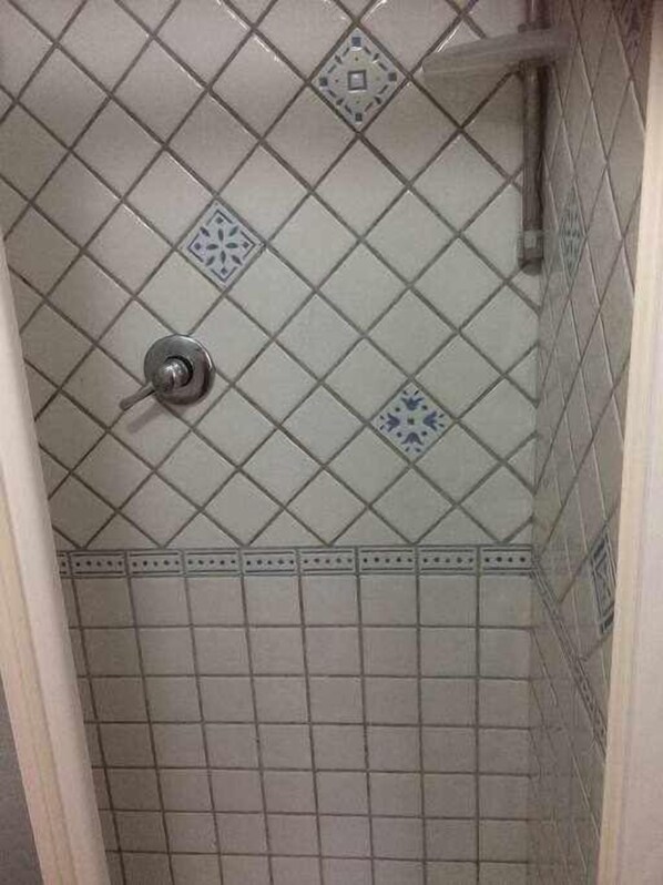 A bathroom with a tiled floor and ceiling, featuring a central shower area with a visible showerhead. - Studio apartment in the Old Town "Donzella" (Alghero)
