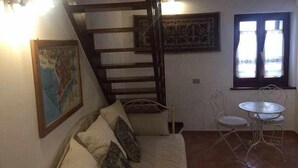 Ein Zimmer mit einem Bett, einem kleinen Tisch, einem Stuhl, einer Treppe und einem Fenster.