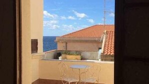 Ein Balkon mit Fliesenboden, einem Tisch und zwei Stühlen.