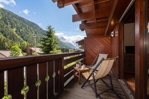 Ein Holzbalkon mit Stuhl und Tisch, mit Blick auf eine Berglandschaft.