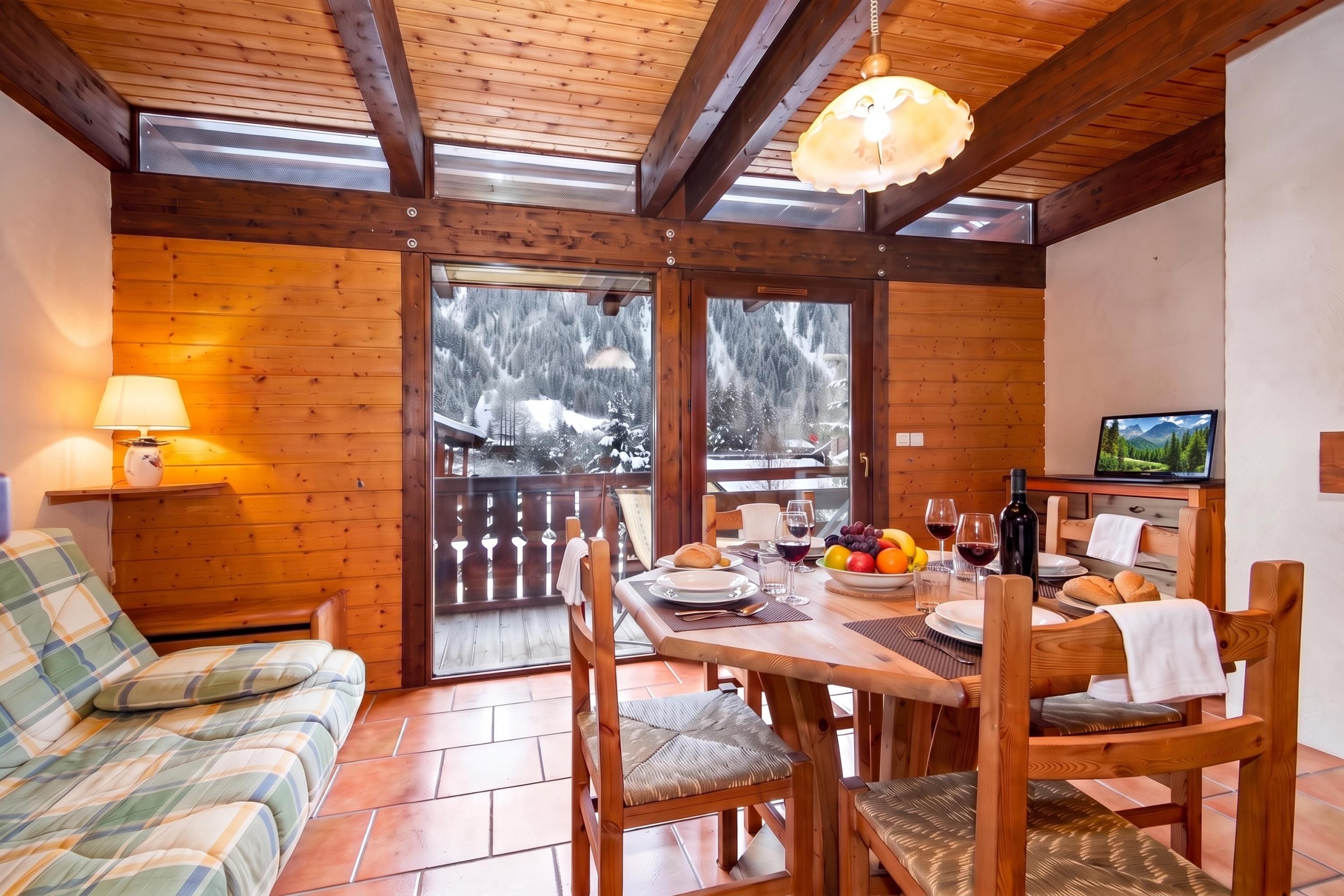A cozy wooden interior with a dining area, a sofa, and a table set for a meal.