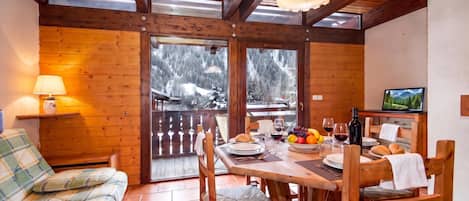 A cozy wooden interior with a dining area, a sofa, and a table set for a meal.