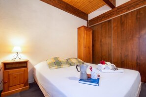 A hotel room with a bed, a wooden wardrobe, a bedside table with a lamp, and a small cabinet. - Chalet Chantey Mourry6 Mountain-View Balcony, Argentière (Chamonix), France (Argentière (Chamonix))
