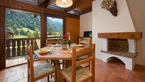 Un espace repas comprenant une table, des chaises, une cheminée et une vue sur les montagnes.