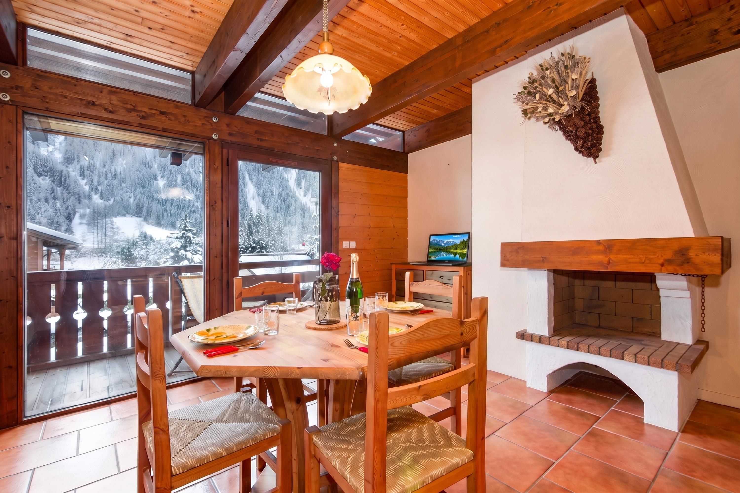 Un intérieur en bois comprenant une table à manger, des chaises, une cheminée et un téléviseur.