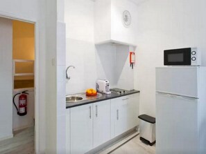 A compact kitchen with white cabinets, a microwave, a coffee maker, and a sink. - Sunny Apartment In City Center (Porto)