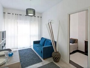 A modern living room with a blue sofa, a coffee table, a TV, and a decorative vase. - Sunny Apartment In City Center (Porto)