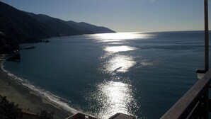 A coastal view with a beach, clear sky, and sunlight reflecting on the water.
