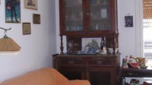A room with a bed, a wooden cabinet with glass doors, and wall-mounted pictures.