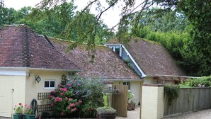 A house with a sloped roof, a wooden fence, and a gravel driveway. - Stables Retreat - Direct Access to The Forest (Burley)