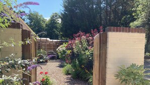 A garden with a gravel path, wooden fence, and various plants. - Stables Retreat - Direct Access to The Forest (Burley)