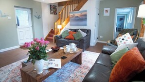 A living room with a sofa, coffee table, and a staircase. - Stables Retreat - Direct Access to The Forest (Burley)