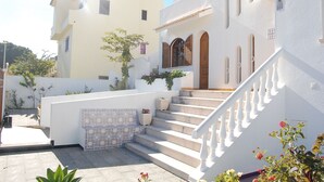 A white building with a tiled entrance, a staircase, and a small garden area. - Large Villa in a relaxing area, with a private Pool and great Sea view. (Forte de São João)