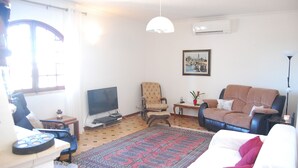 A living room with a sofa, armchair, TV, and a patterned rug. - Large Villa in a relaxing area, with a private Pool and great Sea view. (Forte de São João)