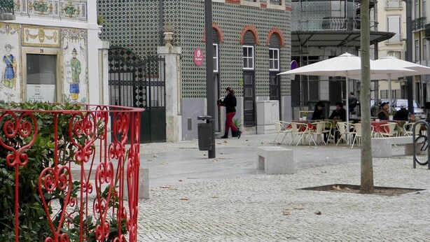 A courtyard with a tiled building, outdoor seating, and a metal fence. - Vintage Apartment in Anjos, Central Lisbon (Lisboa)
