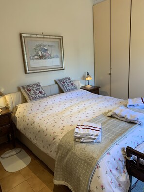 A neatly made bed with floral bedding, a bedside lamp, and a framed picture on the wall.