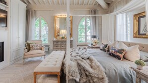 Une chambre spacieuse avec un grand lit, un banc, une commode et un miroir.