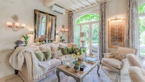 Un salon chaleureux, avec un canapé, un fauteuil et une table basse, agrémenté d’objets décoratifs et d’un grand miroir.