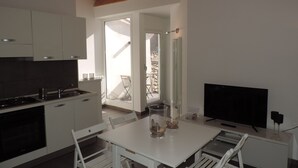 Une cuisine moderne avec des armoires blanches, un four encastré et un coin repas comprenant une table et des chaises blanches.