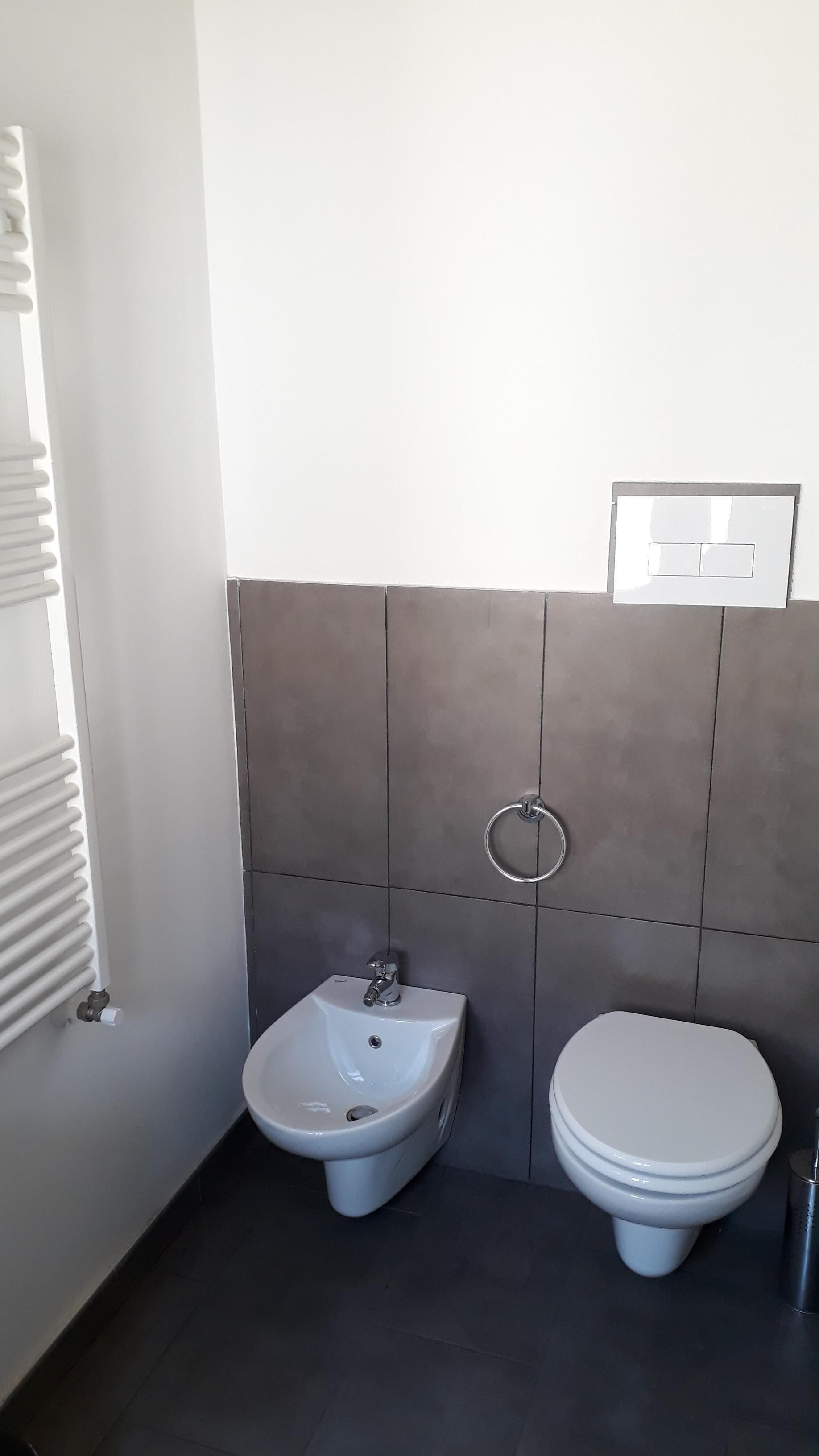 Une salle de bain moderne équipée d’un bidet, de toilettes et d’un porte-serviettes.