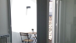 Une petite pièce moderne dotée d’une porte-fenêtre coulissante qui donne sur un espace extérieur aménagé avec une table et des chaises.