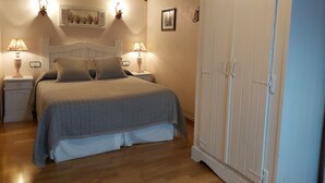 Een slaapkamer met een bed, twee bedlampen, een kledingkast en een lijst aan de muur.