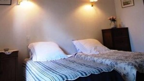 Une chambre à coucher avec un lit, deux lampes fixées au mur, une commode et un tableau encadré accroché au mur.