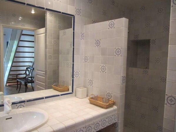 A bathroom with a white sink, a mirror, and a tiled wall with a geometric pattern.