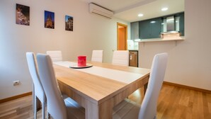Un comedor moderno con una mesa de madera, sillas blancas y una taza roja. Hay tres cuadros en la pared.