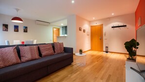 Una sala de estar moderna con un sofá gris oscuro, una mesita redonda blanca y una lámpara colgante.