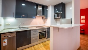 Una cocina moderna con armarios oscuros, electrodomésticos de acero inoxidable, lavavajillas y microondas.