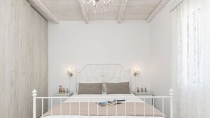 Une chambre à coucher avec un lit blanc, un plafond en bois et un lustre.