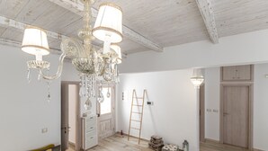 Une pièce spacieuse avec un lustre, un plancher en bois, une échelle et une porte.
