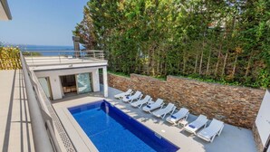 A rooftop pool with lounge chairs, a glass door entrance, and a stone wall. - Beautiful private villa for 8 guests with private pool, A/C, WIFI, TV and patio (Lloret De Mar)