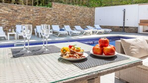 A poolside table with food, glasses, and a view of the pool and lounge chairs. - Beautiful private villa for 8 guests with private pool, A/C, WIFI, TV and patio (Lloret De Mar)
