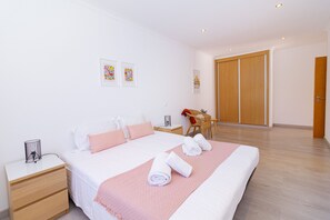 Una habitación de hotel ordenada con una cama grande, una mesita de noche, una silla y un armario.