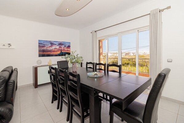 A dining area with a dark wooden table, black chairs, a vase with flowers, and a painting on the wall. - Villa Farol - Villa in Algarve at walking distance to beach, with pool and fast WiFi (Sagres)