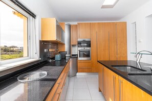 Una cocina moderna con armarios de madera, electrodomésticos de acero inoxidable y encimera negra.
