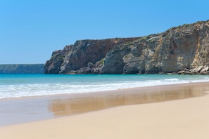 A beach with a rocky cliff and clear blue water. - Villa Farol - Villa in Algarve at walking distance to beach, with pool and fast WiFi (Sagres)