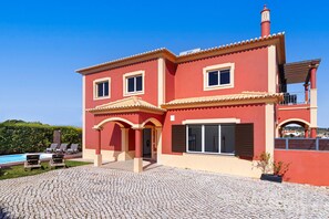 Uma casa de dois andares com fachada vermelha, telhado telhado e uma varanda.