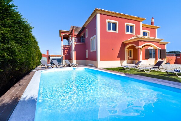 Una casa de dos pisos con piscina, balcón y césped bien cuidado.