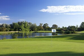 A golf course with a flagstick, water body, and trees. - Villa Farol - Villa in Algarve at walking distance to beach, with pool and fast WiFi (Sagres)