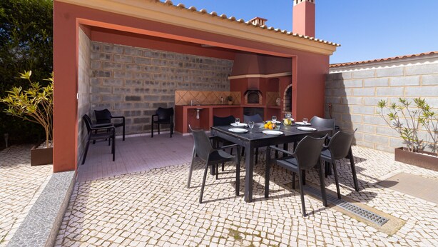 Eine Terrasse im Freien mit einer Ziegelwand, einem gefliesten Boden und einem Esstisch.
