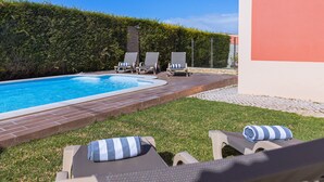 Ein Pool mit Liegestühlen und einer Hecke.