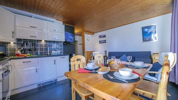 Une cuisine chaleureuse avec des meubles de rangement en bois et un coin repas comprenant une table et des chaises en bois.