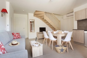 Ein modernes Wohnzimmer mit Sofa, Esstisch, Stühlen, einer Treppe und einer Küchenzeile.