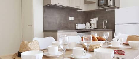 Cozinha moderna com armários brancos, uma máquina de café e um micro-ondas.